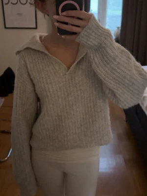 Grå stickad tröja med krage - Grå stickad tröja med bred krage och v-ringad öppning framtill.