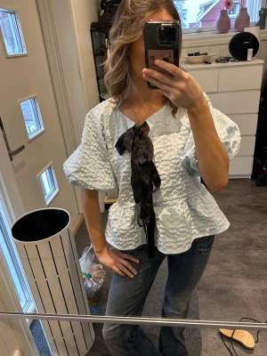 Ljus blå blus - Skit snygg blus från Vera Moda med svarat band som man knyter till rosetter passar till fest och firanden