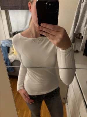 Vit långärmad topp från 157 - Säljer en stilren vit långärmad topp från 157. Toppen har en enkel och tight passform med rund halsringning och är tillverkad i ett mjukt material som känns skönt mot huden. Perfekt att matcha med jeans eller kjol för en clean look.