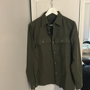  grön overshirt - En stilren overshirts i militärgrönt. Materialet är mjukt och känns som bomull, perfekt nu. Passar dig som är 180-185. Storlek S, skriv om ni har något fundering. 220kr