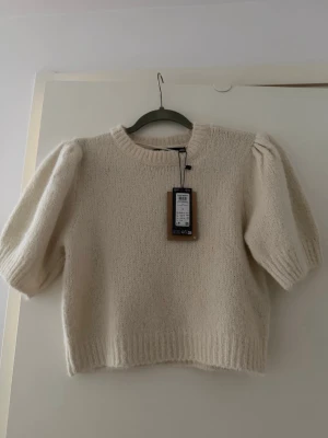 Beige stickad tröja med puffärm - Supersöt beige stickad tröja från Only med puffiga korta ärmar och ribbade muddar. Perfekt till både jeans och kjol för en chill men ändå stylish look. Mjuk och skön, passar perfekt till höst och vår.