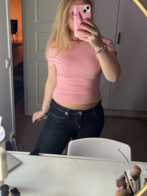 Rosa topp med öppen rygg - Säljer en ljusrosa topp med korta ärmar och öppen rygg. Toppen är figurnära och har en enkel, stilren design som passar perfekt till jeans eller kjol. Lappen är bortklippt men passar S/M