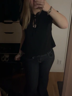 Svart blus med knut - Säljer en svart blus och snygg knytning vid halsen. Blusen har en liten öppning framtill som ger en extra detalj. Passar perfekt till jeans eller kjol och har en lätt, luftig känsla.