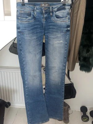 Blå valerie bootcut jeans från LTB - Säljer ett par blå bootcut jeans från LTB med slitningar och ljus tvätt. Låg midja och snygga slitdetaljer framtill. Materialet är jeans i bomull med lite stretch för skön passform.