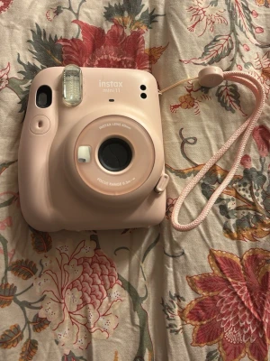 Instax Mini 11 - Snygg rosa Instax Mini 11 direktfilmskamera i fint skick. Levereras med matchande lila väska och fotoalbum. Perfekt för att ta och spara minnen direkt. Inga synliga defekter eller slitage, redo att användas direkt! Jag tar även emot bud!
