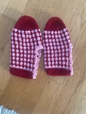 Handvirkade tofflor i rött och rosa - Unika handvirkade tofflor i rött och ljusrosa med ett bubbligt mönster. De är mjuka och sköna att ha på sig inomhus och har en rund tå. Perfekta för att hålla fötterna varma under kyliga dagar.