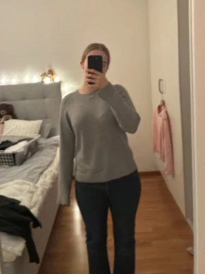 Grå stickad tröja från Vero Moda - Mysig grå stickad tröja från Vero Moda i storlek S. Tröjan har rund halsringning, långa ärmar och ribbade muddar. Perfekt för lager-på-lager och chill dagar. Enkel och stilren design som funkar till det mesta.