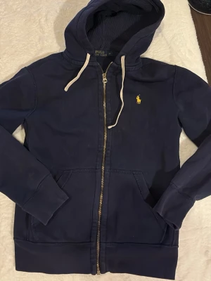 Ralph lauren mörkblå zip-hoodie - Mörkblå zip-hoodie från Ralph lauren. Använd men i gott skick. Lite urtvättad men fortfarande väldigt stilsäker