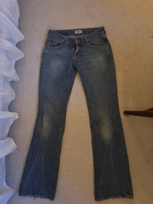 Blå bootcut jeans från Tommy Hilfiger - Snygga blå jeans från Tommy hilfiger  med bootcut passform och låg midja, slitningar framtill