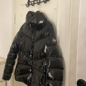 Svart glansig pufferjacka från Colmar - Säljer en svart, glansig pufferjacka från Colmar som är en vinterjacka. Den är jättesnygg men fortfarande varm. Köpte för ca ett år sen men inte använt jättemycket och den är fortfarande i jättebra skick. Det är storlek M men passar ändå mig som är S/M skriv för fler bilder Elr frågor💞💞