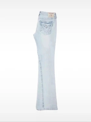 Ljusblå bootcut jeans från True Religion - Snygga ljusblå jeans från True Religion med klassisk bootcut-passform och fem fickor. Jeansen är i joey modell, de har blivit lite använda och är slitna nere men inget man tänker på och de är dessutom äntå långa i benen. Säljer då de inte passar mig längre. 💗💗 Snälla köp jag behöver pengarna🥰🙏🏻🙏🏻