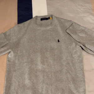 Grå stickad tröja från Polo Ralph Lauren - Snygg grå stickad tröja från Polo Ralph Lauren med klassisk. Perfekt nu när det börjar bli kallt passar det perfekt med en sådan tröja. Skriv gärna vid frågor. 