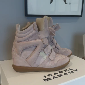 Isabel Marant Bekett sneakers rosa  - Säljer mina ikoniska Bekett sneakers från Isabel Marant i ljusrosa mocka med beige detaljer och gummisula. Skorna har dold kilklack, kardborreband och en cool, sportig siluett som ger extra höjd. Perfekta för dig som vill ha en trendig och bekväm look. Lite smutsiga skosulor vid tårna men inget märkvärdigt! Man får med kartongen och påsen till💗passar dig som har storlek 39-40 då dem är små i storleken. Nypris är 6500kr och helt slut på hemsidan därför högt pris. Men priset kan diskuteras!