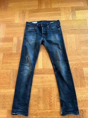 Replay Grover jeans straight fit blå - Snygga Replay Grover jeans i straight fit med klassisk femficksdesign. Färgen är mörkblå med coola slitningar och tvättade detaljer. Jeansen har normal passform och är tillverkade i slitstarkt denim. Perfekt för dig som gillar en stilren och avslappnad look.