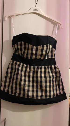 Svartvit rutig peplum top Paris Kate & I - Supersöt peplum top från Paris Kate & I i storlek 34. Toppen är axelbandslös med svart överdel och breda svarta kanter, samt ett rutigt mönster i svart och beige. Överdelen sitter som en korsett!!.😍