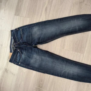 Mörkblå jeansbyxor George, storlek 31 - Snygga mörkblå jeansbyxor från George i klassisk femficksmodell. Jeansen har kontrastsömmar och lätt slitna detaljer framtill och baktill för en cool look. Passformen är rak med normal midja och materialet är robust denim.