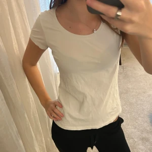 Vit basic t-shirt med rund hals - En enkel och fräsch vit t-shirt med rund hals och korta ärmar. Modellen är klassisk och sitter snyggt med en normal passform. Perfekt att matcha med jeans eller shorts. Materialet känns mjukt och bekvämt mot huden.