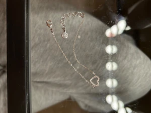 Silverarmband med hjärta  - Snyggt och tunt armband i äkta silver med ett glittrigt hjärta i mitten, dekorerat med små cubic zirconia-stenar. Justerbar längd med karbinlås och stämpel 925. Perfekt för dig som gillar stilrena smycken med en touch av bling.  Täcken på användning vid slutet av kedjan men annars i fint skick