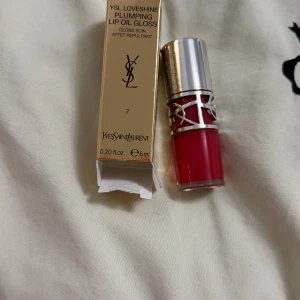 YSL Loveshine Plumping Lip Oil Gloss - YSL Loveshine Plumping Lip Oil Gloss i färg 7, med en lyxig röd nyans och glansig finish. Snygg förpackning med silvrigt lock och YSL-logga i metall runt flaskan. Innehåller 6 ml och kommer i en elegant guldig kartong.