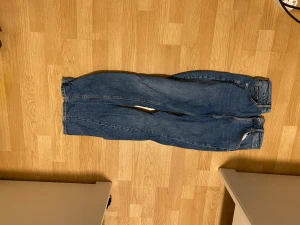 Vintage slim high waist jeans strl 36 - Snygga blå jeans med vintagekänsla, slim fit och hög midja. Klassisk femficksmodell med gul kontrastsöm och raka ben. Perfekt för dig som gillar en tidlös och clean look. Storlek 36.