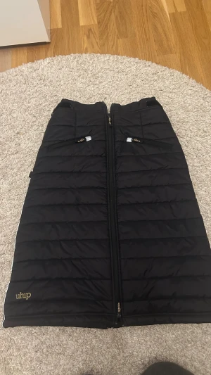 Svart långkjol från Uhip med dragkedja - Svart quiltad långkjol från Uhip med hel dragkedja framtill och två dragkedjefickor. 