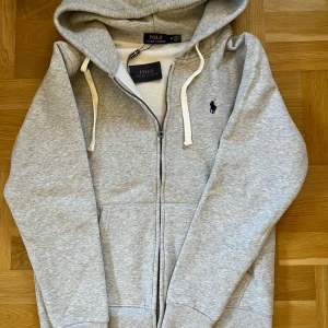 Grá hoodie fràn Polo RalphLauren - Har ingen användning enda sen jag köpte den, helt ny aldrig haft pả mig sen ute bara testat inomhus. OBS: Kom med bud sả kan vi förhandla!