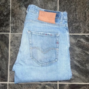 Replay jeans  - Säljer ett par ljusblå skinny jeans från Replay med klassisk femficksdesign och läderpatch bak. Jeansen har en smal passform och är tillverkade i jeansmaterial med snygga slitningar framtill. Midja 41cm, längd 98cm. JAG SKICKAR EJ FLER BILDER NÄR JAG BÄR JEANSEN! för storleksguide hänvisar jag till måtten och för bättre inblick i passformen rekommenderar jag att googla på modellnamnet. Jeansen kan vara uppsydda utan att jag noterat det så kolla måtten noggrant :) s4 