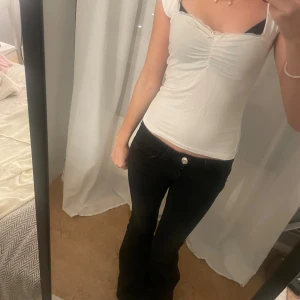 Spets topp - Säljer en vit croppad topp från 157 i storlek S. Toppen har korta ärmar, söt spetskant vid halsringningen och en lätt rynkning framtill.