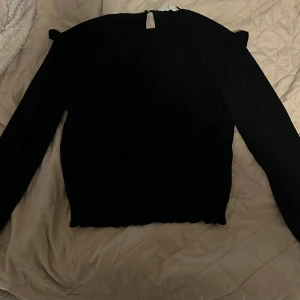 Svart långärmad tröja  - Liten tunnare finare tröja från H&M. Tröjan är svart i storlek 170 och har fina detaljer. Passar perfekt om man vill ha en fin men ändå chill look. Passar både för vardagar och finare dagar.