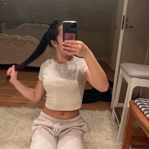 Vit croppad ribbad topp - Säljer en vit croppad topp med korta ärmar och rund hals. Toppen är ribbad och har en tight passform som sitter snyggt på kroppen. Perfekt till jeans eller mjukisbyxor för en chill look. på slutet har dom två jätte små fläckar som jag int ens märkte förens jag tog kort