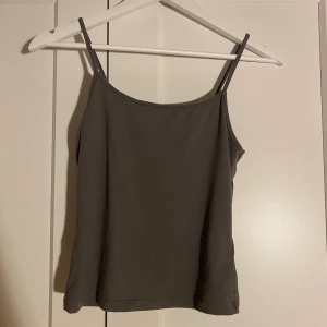 Grått linne - Säljer ett enkelt och stilrent grått linne  från H&M Divided i storlek S. Toppen har smala axelband och rak passform, perfekt för att styla med jeans eller kjol. Materialet är mjukt och skönt.