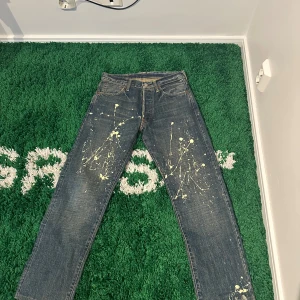 Evisu Blåa Jeans - Skriv för mått! Evisu jeans med en unik design med färgstänk. Jeansen har en klassisk passform och detaljer som de karakteristiska måsvingarna på bakfickorna. Storlek 30/32. Väldigt fint skick!