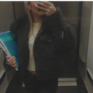 Meotine kappa - Säljer en fluffig och mysig mörk teddyjacka med stor krage. Jackan har en boxig passform och är perfekt för kyliga dagar. Stängs med knappar framtill och har en cool, trendig look som passar till jeans eller kjol. Denna modellen på jackan säljs inte längre 