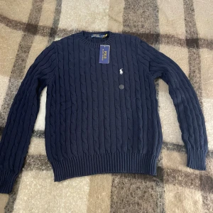 Polo Ralph Lauren marinblå - Marinblå kabelstickad tröja från Polo Ralph Lauren som är perfekt för daglig kofta eller kalla ute dager❄️, tröjan är i S storlek och är i utmärkt skick 10/10 och medföljer Polo taggen. Pris kan diskuteras och om du har intresse eller frågor, är bara kontakta mig🤝