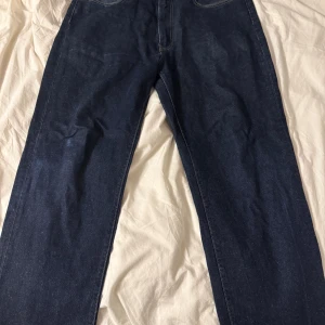 Levi's 560 Stay Loose jeans mörkblå - Mörkblå Levi's 560 Stay Loose jeans med klassisk femficksdesign och raka ben. Jeansen har en loose fit och är tillverkade i robust denim med kontrastsömmar och läderpatch bak i midjan. Perfekta för dig som gillar avslappnad stil. Litet slitage på höger knä som syns på sista bilden.