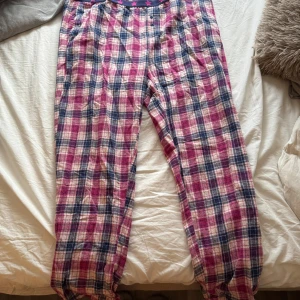 Rutig mjukisbyxa från Esmara L - Säljer ett par rutiga mjukisbyxor från Esmara i storlek L. Byxorna har en skön resår i midjan med stjärnmönster och är gjorda i mjukt bomullsmaterial. Färgerna är rosa, blå och vit, perfekt för chill dagar hemma.