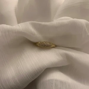 Guldfärgad ring med glittriga stenar - Snygg guldfärgad ring mez glittriga små stenar på ovansidan. Helt ny, storlek 7