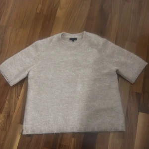 Beige stickad tröja från Stockh LM - Supermjuk och stilren beige stickad tröja från Stockh LM. Tröjan har korta ärmar, rund halsringning och ribbade kanter. 