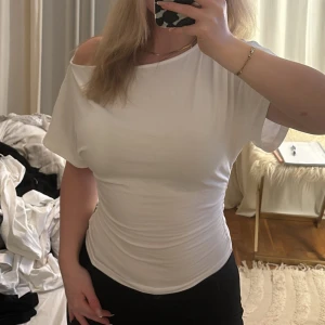 Vit offshoulder topp i bomull - Säljer en vit, tight offshoulder topp i mjuk bomull. Toppen har korta ärmar och sitter snyggt figurnära med en clean och enkel look. 