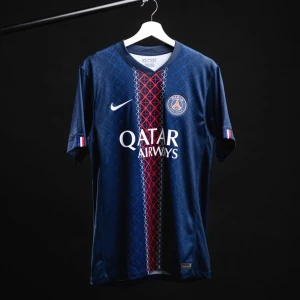 PSG matchtröja 25/26 - Säljer en officiell Paris Saint-Germain matchtröja från Nike i marinblått med geometriskt mönster och röd-vit rand längs mitten. PSG-logga på bröstet, Qatar Airways tryck och korta ärmar. Perfekt för dig som älskar fotboll och vill representera PSG.
