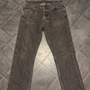 Svarta jeans från Weekday - Säljer ett par svarta jeans från Weekday i klassisk femficksmodell. Jeansen har rak passform och normal midja, tillverkade i bomull. Snyggt slitna detaljer och silverfärgade knappar. Perfekt för dig som gillar enkel och stilren look. 29/30