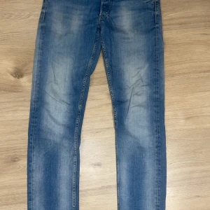 Replay Grover blå jeans slim fit - Snygga blå jeans från Replay med klassisk femficksdesign och brunt läderpatch bak. Jeansen har en slim fit och ljus tvätt med slitningar på låren. Passar dig som gillar en tidlös look och vill ha ett par jeans som funkar till allt.
