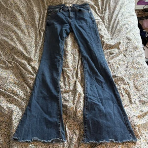 Blå flare jeans från Mango, strl 34 - Snygga blå jeans från Mango i modell flare med riktigt utsvängda ben och råa, fransiga benslut. Klassisk femficksdesign och normal midja. Jeansen är gjorda i denim och har en cool vintage vibe. Perfekta för dig som gillar statementbyxor!