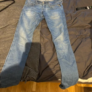 Replay Anbass slim fit jeans blå 31/34 - Säljer ett par Replay Anbass slim fit jeans i klassisk blå tvätt. Jeansen har fem fickor, snygga detaljer på bakfickorna och normal midja. Materialet är mjukt denim i bomull med lite stretch för extra komfort. Perfekta för dig som gillar en smalare passform.