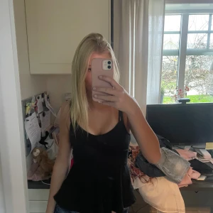 Svart linne med volang - Säljer ett svart linne med ribbat tyg. Tröjan är i bra skick, knappt änvänd💗