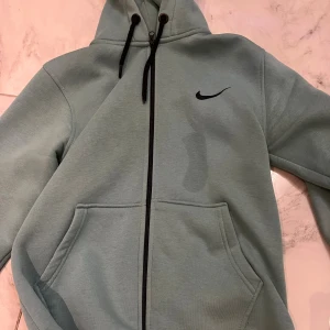 Grön hoodie  - Snygg ljusgrön.Tröjan har hel dragkedja, huva med snörning och två stora fickor framtill. Perfekt för en chill och sportig look.