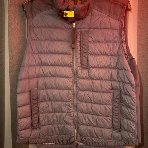 Navy Blue dunväst Parajumpers Remix L - Snygg Navy blue dunväst från Parajumpers Remix i storlek L. Västen har quiltad design, hög krage med gul detalj, flera fickor med dragkedja och markerade axelpartier. Perfekt för lager-på-lager och streetwear. Stängs med dragkedja framtill. (Pris kan diskuteras) 