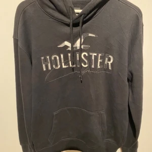 Holister hoodie - En hoodie med perfekt passform och premiumkänsla. Inspirerad av klassisk Hollister-stil – avslappnad men stilren. Tillverkad i mjuk bomullsblandning med borstad insida för extra komfort. Ribbstickade muddar och justerbar huva med snörning ger en lyxig street-look. Passform: Regular-fit (sitter snyggt men inte för tight). Storlek: s Design: Enkel, ren logga på bröstet eller ton-i-ton broderi.