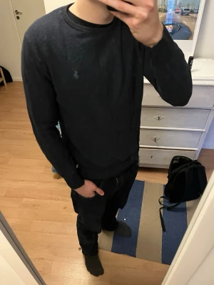 Mörkblå tröja från Polo Ralph Lauren - Säljer en mörkblå långärmad tröja från Polo Ralph Lauren i mjuk pima bomull. Tröjan har rund hals, diskret logga broderad på bröstet och ribbade muddar vid ärmslut och nederkant. Perfekt för dig som gillar stilrena och klassiska plagg.