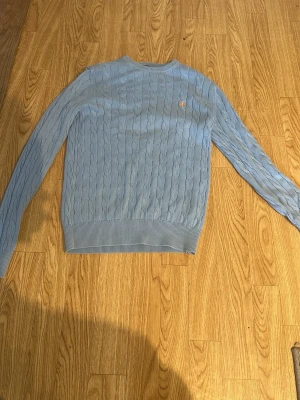 Ljusblå kabelstickad tröja Morris - Säljer en ljusblå kabelstickad tröja med ett orange märke från Morris i 100% pima bomull. Tröjan har rund hals och är en väldig fin tröja främst med mönstrerna, storlek s passar också xs, ingen defekt på tröjan, har haft den i någon månad personen är 164 cm på bilden, mycket bra skick på tröjan. Nypris 1500 kr, om ni har någon fråga meddela gärna😀